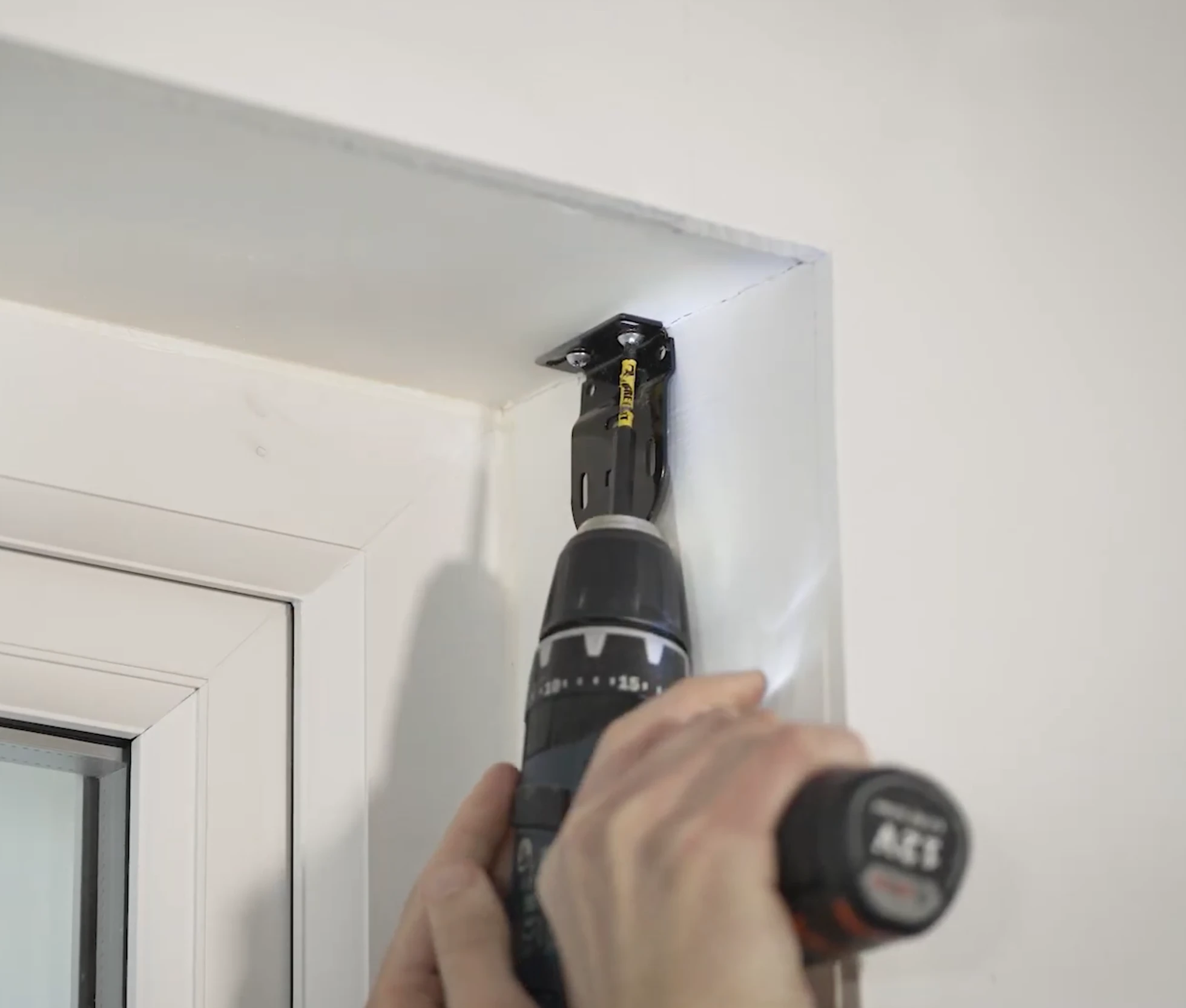 Cordless drill fixing a bracket during roller blind installation
